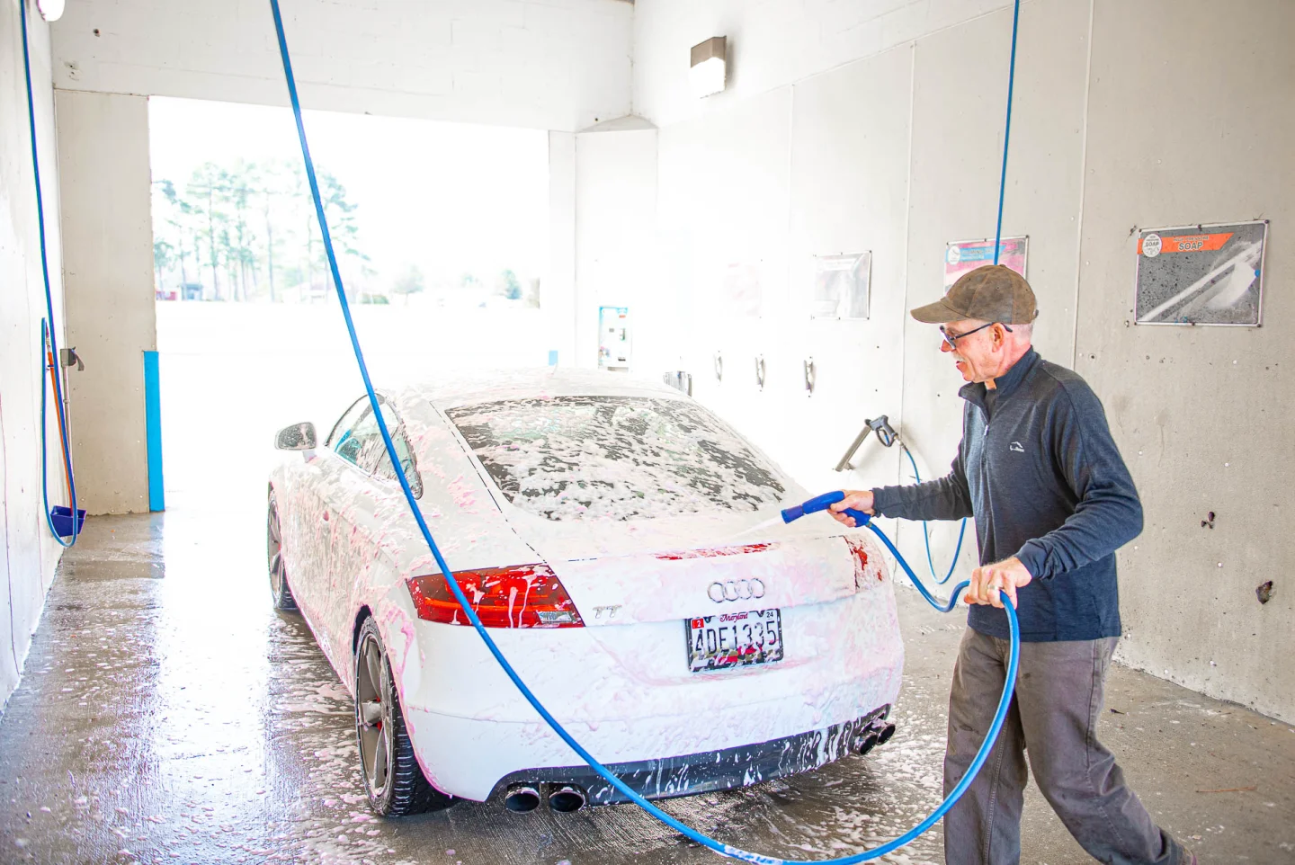 Customer washing a white Audi TT covered in foam inside the GO! Wash Easton II self-serve bay