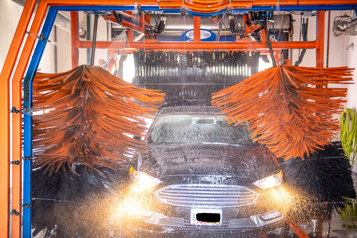 Car moving through the GO! Wash Easton tunnel with orange foam brushes