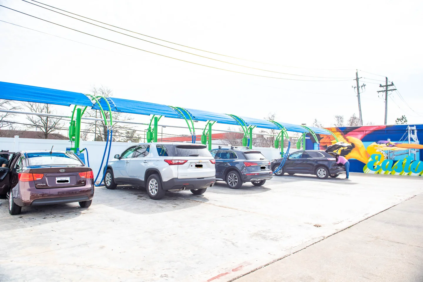 Customers using free vacuum stations at GO! Wash Easton I with the Easton mural visible
